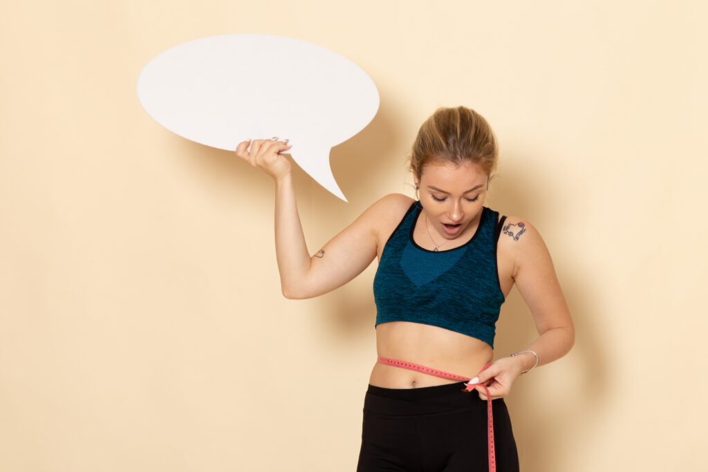 front view young female sport outfit holding white sign measuring her body
